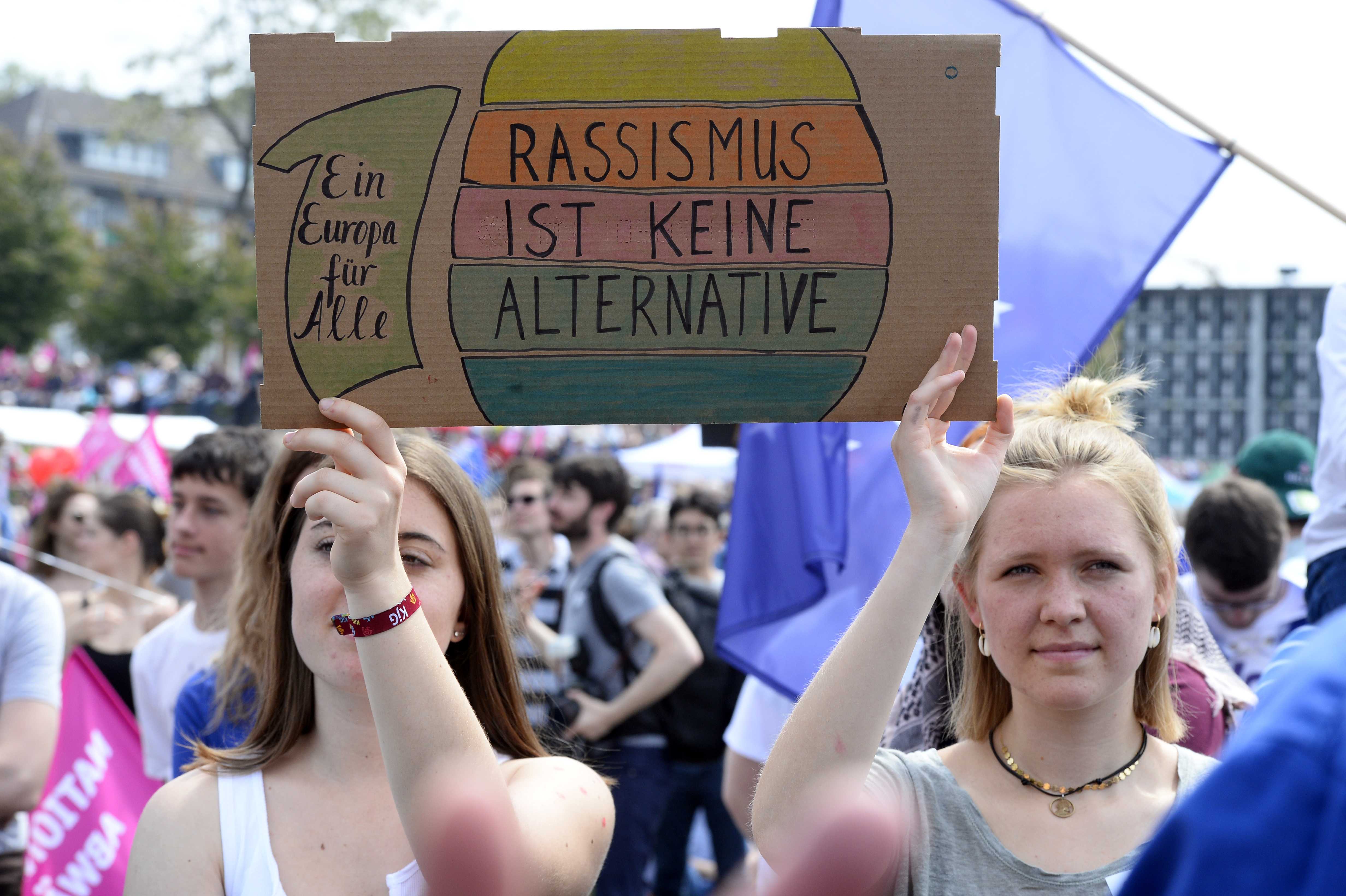 Zwei Frauen mit einem Schild "Rassissmus ist keine ALternative" stehen bei einer Demonstration für Europa