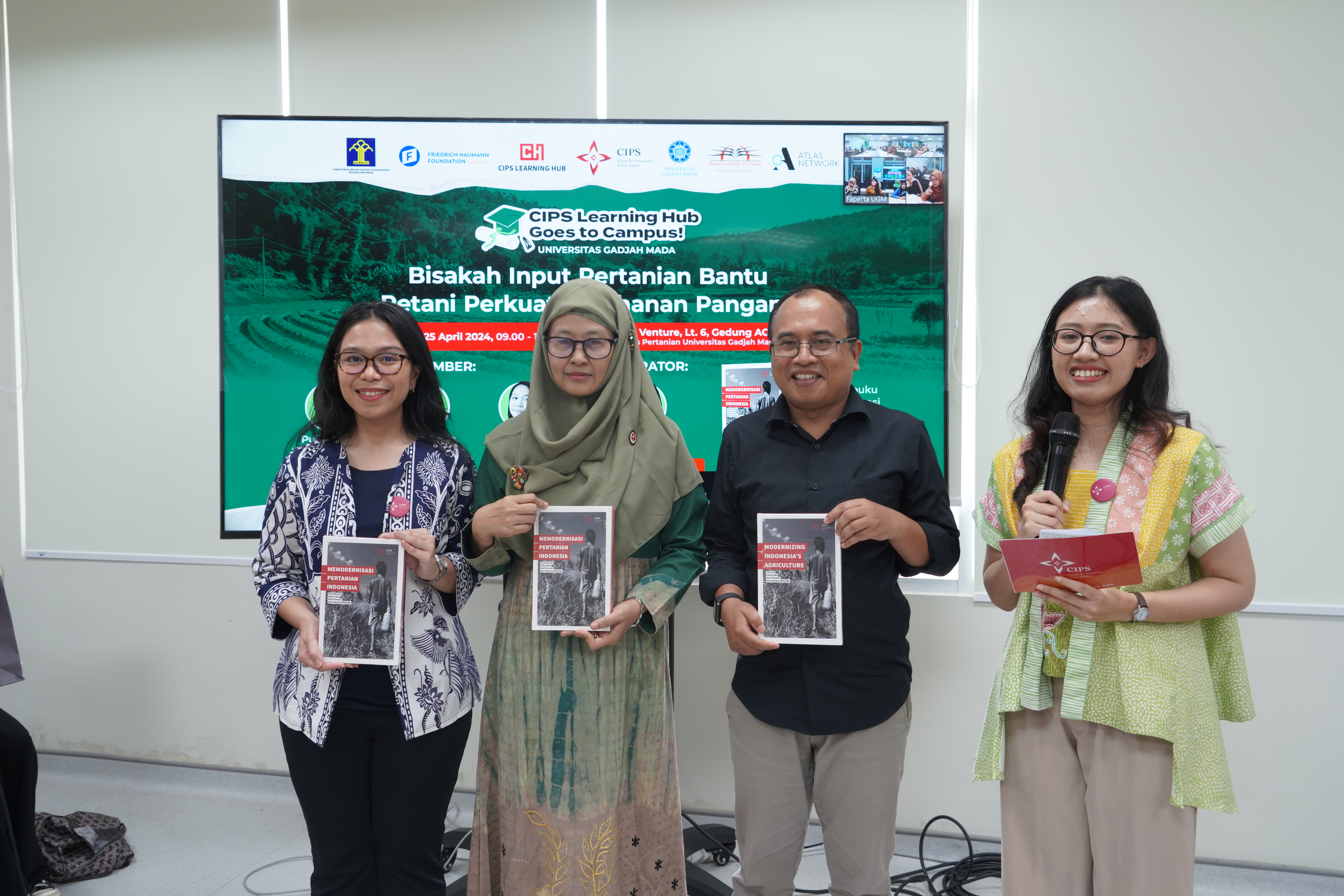The three speakers are standing next to the Emcee, each of them holding a book published by CIPS titled, "Modernizing Indonesia's Agriculture".