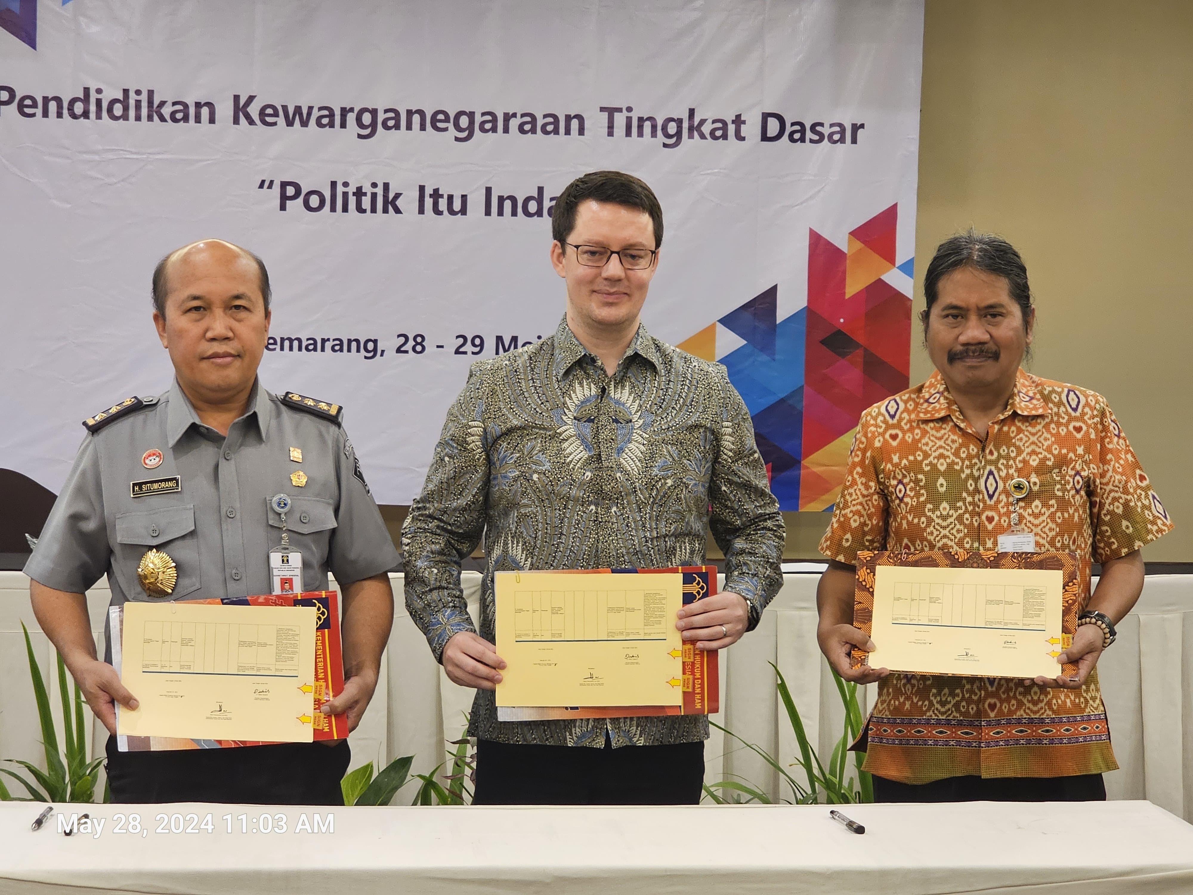 Hantor Situmorang (Head of Bureau of Public Relations, Law, and Cooperation at Ministry of Law and Human Rights Indonesia), standing alongside Dr. Stefan Diederich (Project Director at FNF Indonesia) and Agung Kristianto (Representative of the Head of the Office of National Unity and Politics of the Central Java Provincial Government). The three of them were holding the Annual Work Plan undertaken by each of their respective organizations.