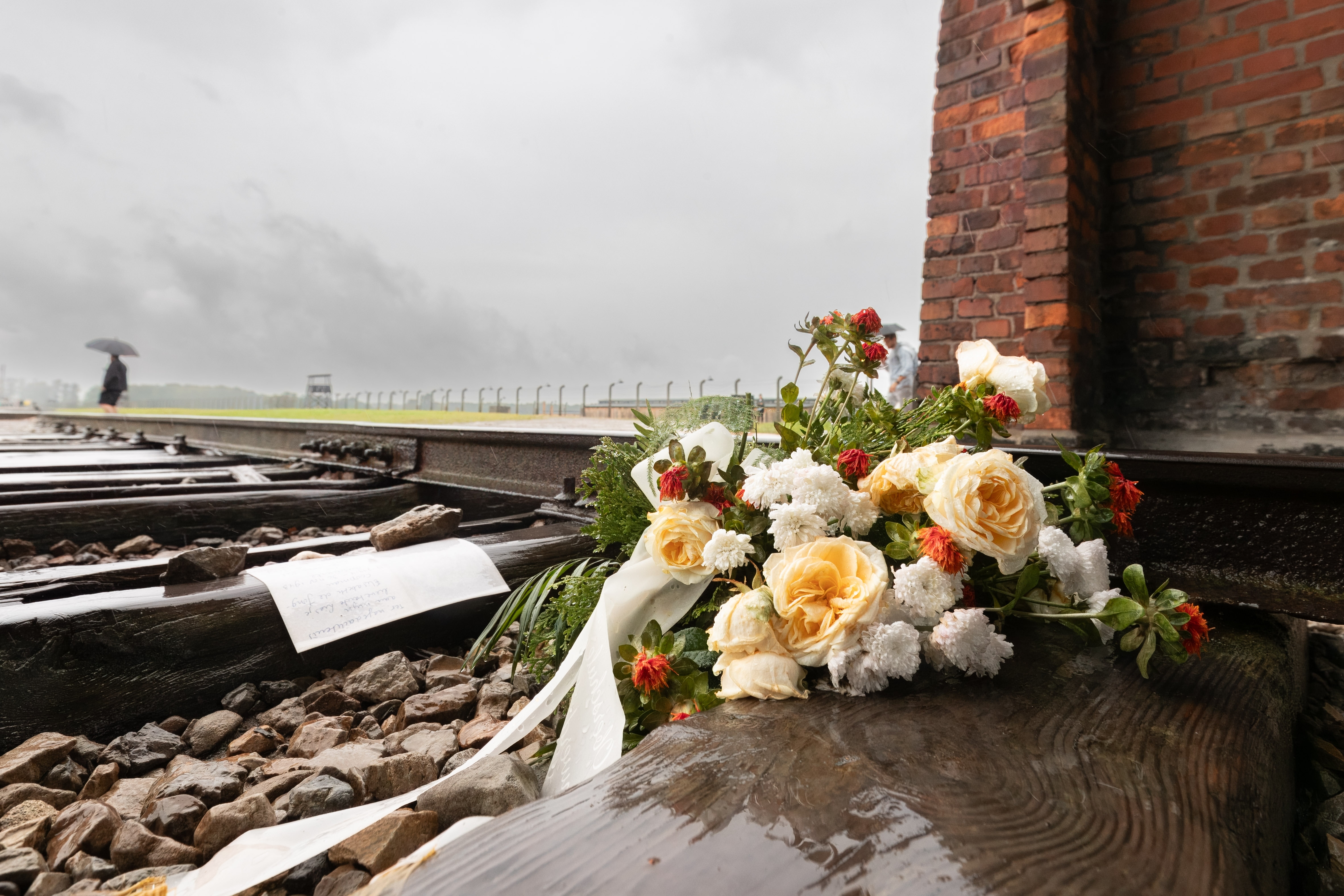 KZ Auschwitz Besucher haben an dem Einfahrttor zum Konzentrationslager Auschwitz-Birkenau Blumen auf die Schienen auf denen massenweise Gefangene angekommen sind abgelegt.