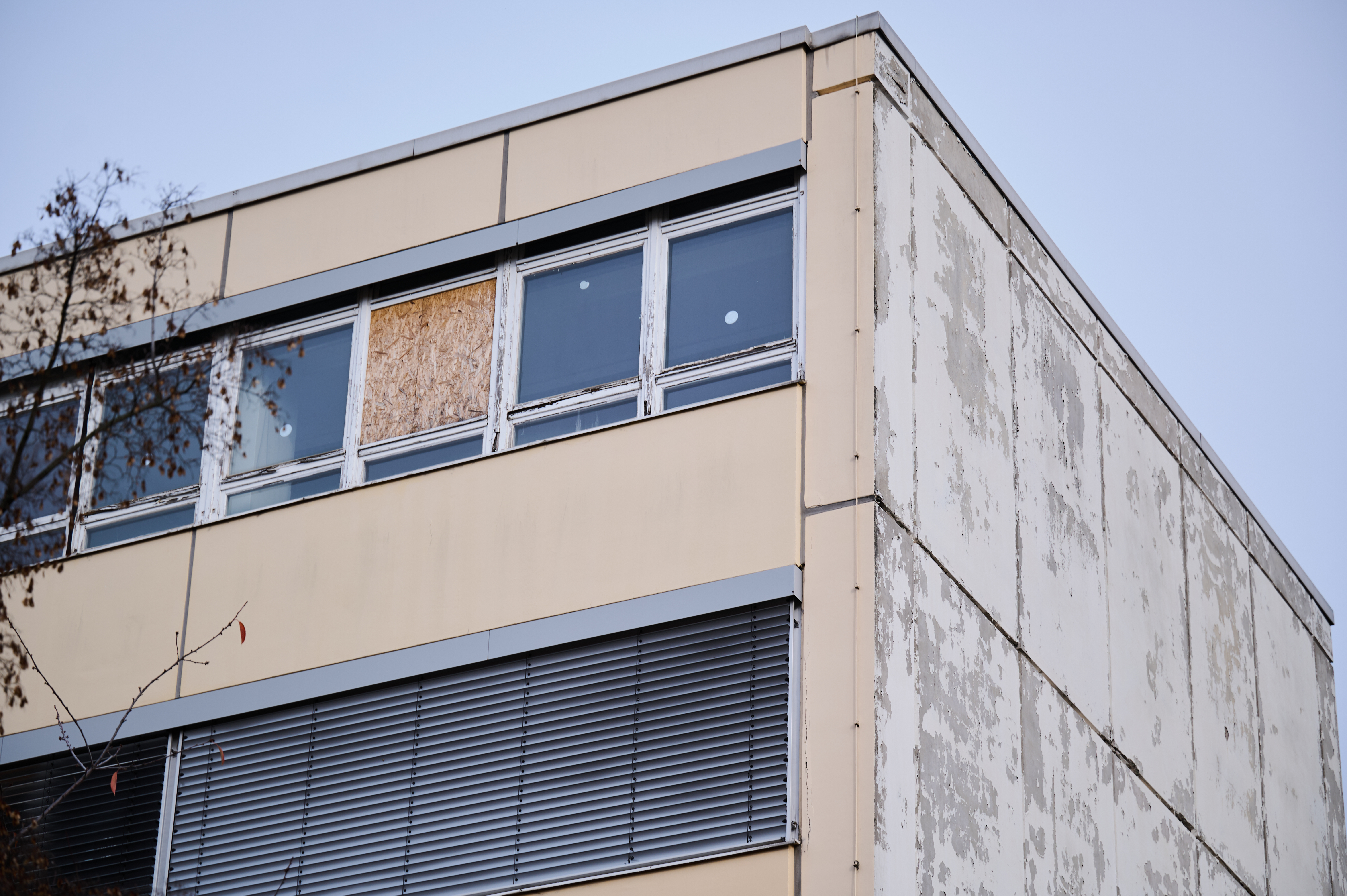 Ein Fenster des Gymnasiums am Europasportpark (GESP) ist provisorisch mit Holz verschlossen, während an den anderen Fenstern Aufkleber kleben, die anzeigen, dass diese Fenster nicht geöffnet werden dürfen. Dem Gymnasium droht wegen ausbleibender Sanierung die Schließung. 
