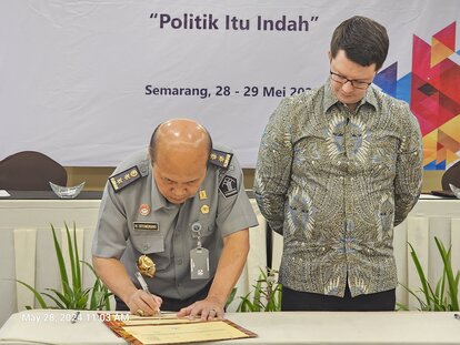 Hantor Situmorang signing the Annual Work Plan document. Dr. Stefan Diederich was seen stood next to him.