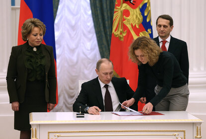 Der russische Präsident Wladimir Putin (sitzend) unterzeichnet ein Dekret zur Eingliederung der Krim