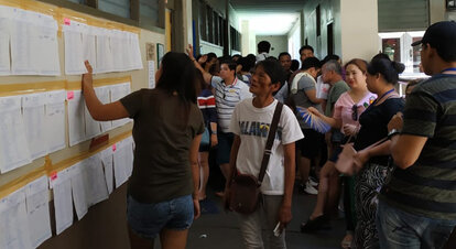 People look for their names from the Lists of Registered voters posted outside polling precincts.