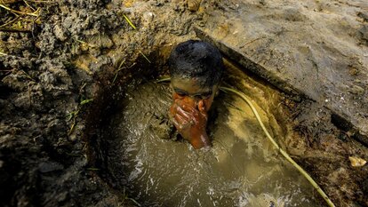 Ein Junge wischt sich den Schlamm aus den Augen, nachdem er eine Stunde lang mit Kompressorluft in 12m tiefem Schlammwasser getaucht ist. Stadt Paracale, Camarines Norte