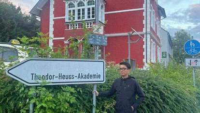 Rahman Imuda standing next to a signboard on which written, "Theodor-Heuss-Akademie".