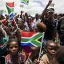 Mit Regenbogenfahnen wedelnde Unterstützer Mandelas auf dessen Beerdigung 2013