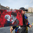 Ukrainischer Demonstrant hält Bild von Putin und Ayatollah beim Küssen