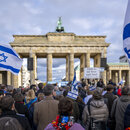 Teilnehmer der Kundgebung „Aufstehen gegen Terror, Hass und Antisemitismus – in Solidarität und Mitgefühl mit Israel“ vor dem Brandenburger Tor schwenken israelische Flaggen.