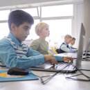 Junge beim E-Learning mit Laptop am Schreibtisch in der Schule