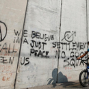 Ein arabischer Junge fährt im Osten Jerusalems auf einem Rad am Trennwall zwischen Israel und den palästinensischen Gebieten entlang.