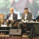 A photo of one of the sessions in Malaysia Outlook Conference 2024. Four people are sitting on individual chairs in front of a big screen on the stage. They are: Aira Azhari (Moderator), Ibrahim Suffian (Panelist), Ooi Kok Hin (Panelist), and Datuk Dr. Johan Arriffin Samad (Panelist).