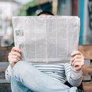 Persona leyendo un diario en una banca