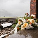 KZ Auschwitz Besucher haben an dem Einfahrttor zum Konzentrationslager Auschwitz-Birkenau Blumen auf die Schienen auf denen massenweise Gefangene angekommen sind abgelegt.