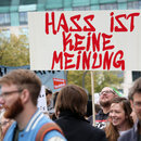 Mit Schildern, unter anderem mit der Aufschrift "Hass ist keine Meinung", ziehen Teilnehmer bei einer bunten Parade gegen Rassismus durch die Innenstadt. 