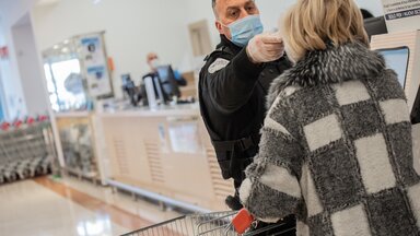Eine Frau wird vor dem Betreten des Supermarktes auf Fieber kontrolliert.