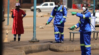 Reinigungskräfte deifizieren hier eine Busstation in Harare. 