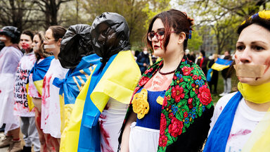 Frauen protestieren vor dem Bundeswirtschaftsministerium in weißer Kleidung mit künstlichem Blut darauf sowie verbundenen Händen bei einer Demonstration gegen die Gewalt an Frauen und Mädchen beim russischen Angriffskrieg auf die Ukraine. 