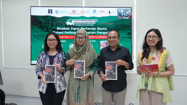 The three speakers are standing next to the Emcee, each of them holding a book published by CIPS titled, "Modernizing Indonesia's Agriculture".