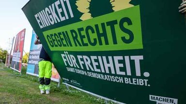 Zwei Mitarbeiter einer Firma für Werbeaufsteller bauen ein Wahlplakat der Partei „Bündnis 90/Die Grünen“ nach der Europawahl ab