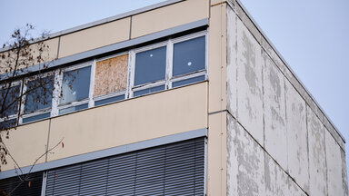 Ein Fenster des Gymnasiums am Europasportpark (GESP) ist provisorisch mit Holz verschlossen, während an den anderen Fenstern Aufkleber kleben, die anzeigen, dass diese Fenster nicht geöffnet werden dürfen. Dem Gymnasium droht wegen ausbleibender Sanierung die Schließung. 