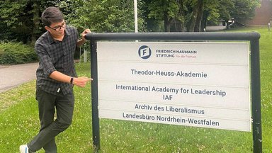 Rahman Imuda standing next to a signboard of IAF in Gummersbach.