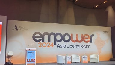 A view of the Asia Liberty Forum 2024's stage. A podium is seen standing a few metres apart from three single seats reserved for speakers.